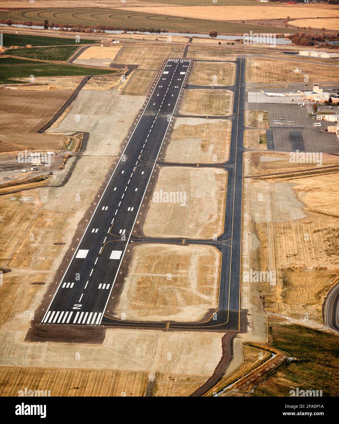 Die Start- und Landebahn, der Rollweg, das Terminal und das Parken von Flugzeugen an den Idaho Falls, dem Flughafen der Stadt Idaho, werden in der Abenddämmerung aufgenommen, um die Landescheinwerfer und Markierungen zu zeigen. Stockfoto