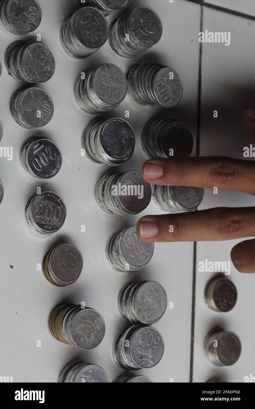 Mann, der indonesischen Penny zählt. Gestapelte Rupiah-Münze. Stockfoto