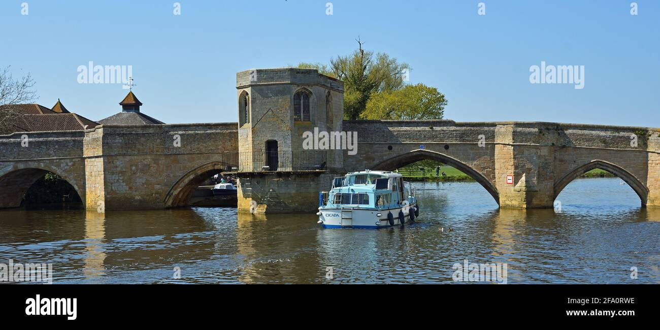 ST IVES, CAMBRIDGESHIRE, ENGLAND - 19. APRIL 1021: Historische Brücke über den Fluss Ouse in St Ives Cambridgeshire mit Flusskreuzfahrtschiff Stockfoto