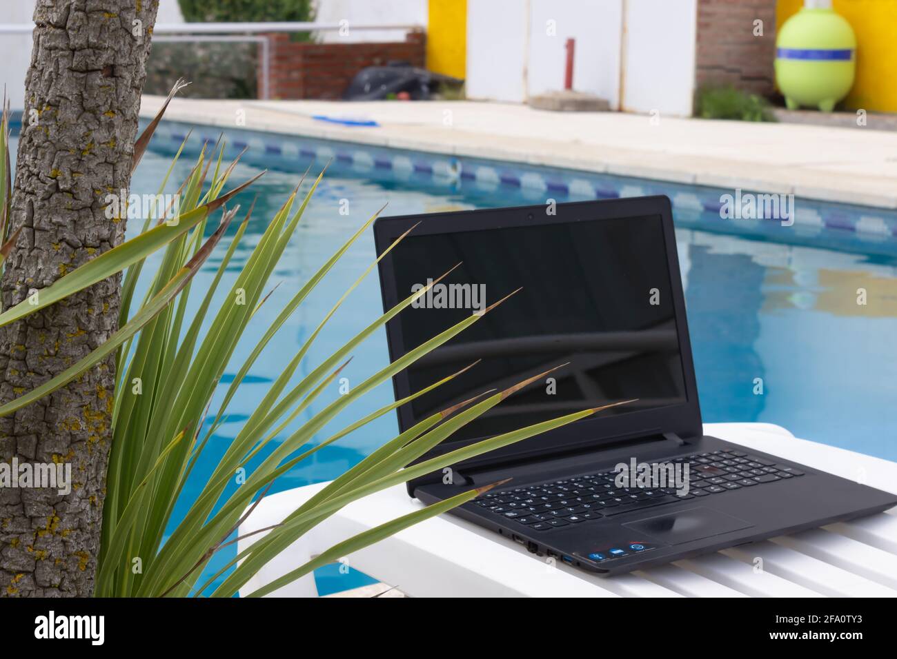 Notebook auf einer Sonnenliege am Pool. Stockfoto