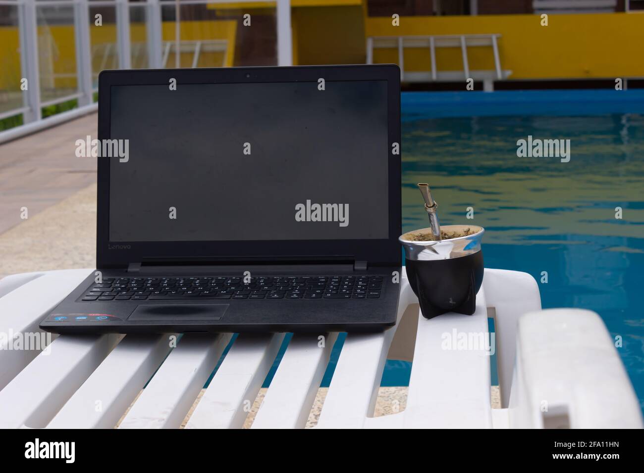 Notebook und paaren Sie sich auf einer Sonnenliege am Pool. Stockfoto