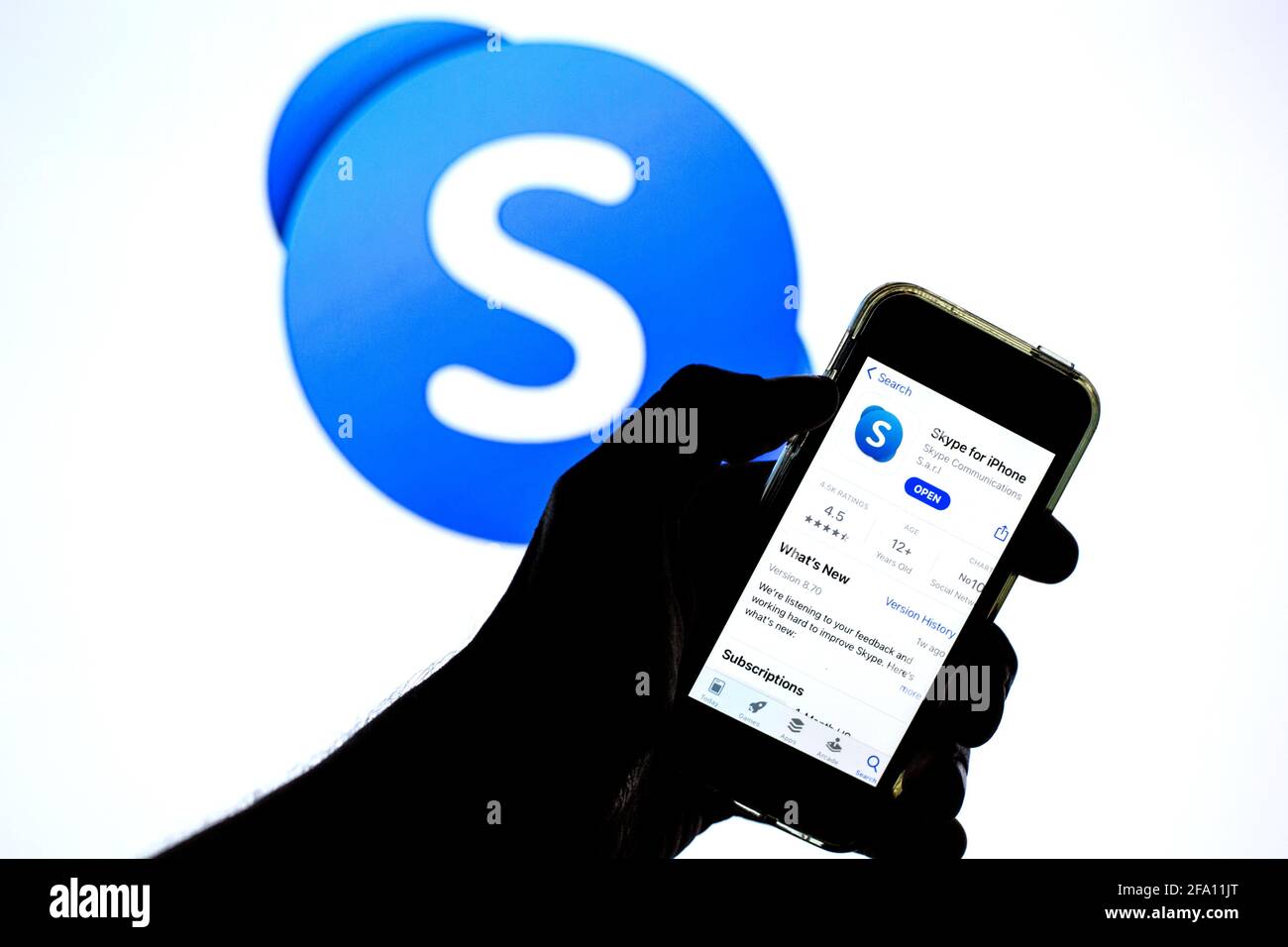 In dieser Abbildung wird eine Skype-App im App Store auf einem Smartphone mit dem Skype-Logo im Hintergrund angezeigt. Stockfoto