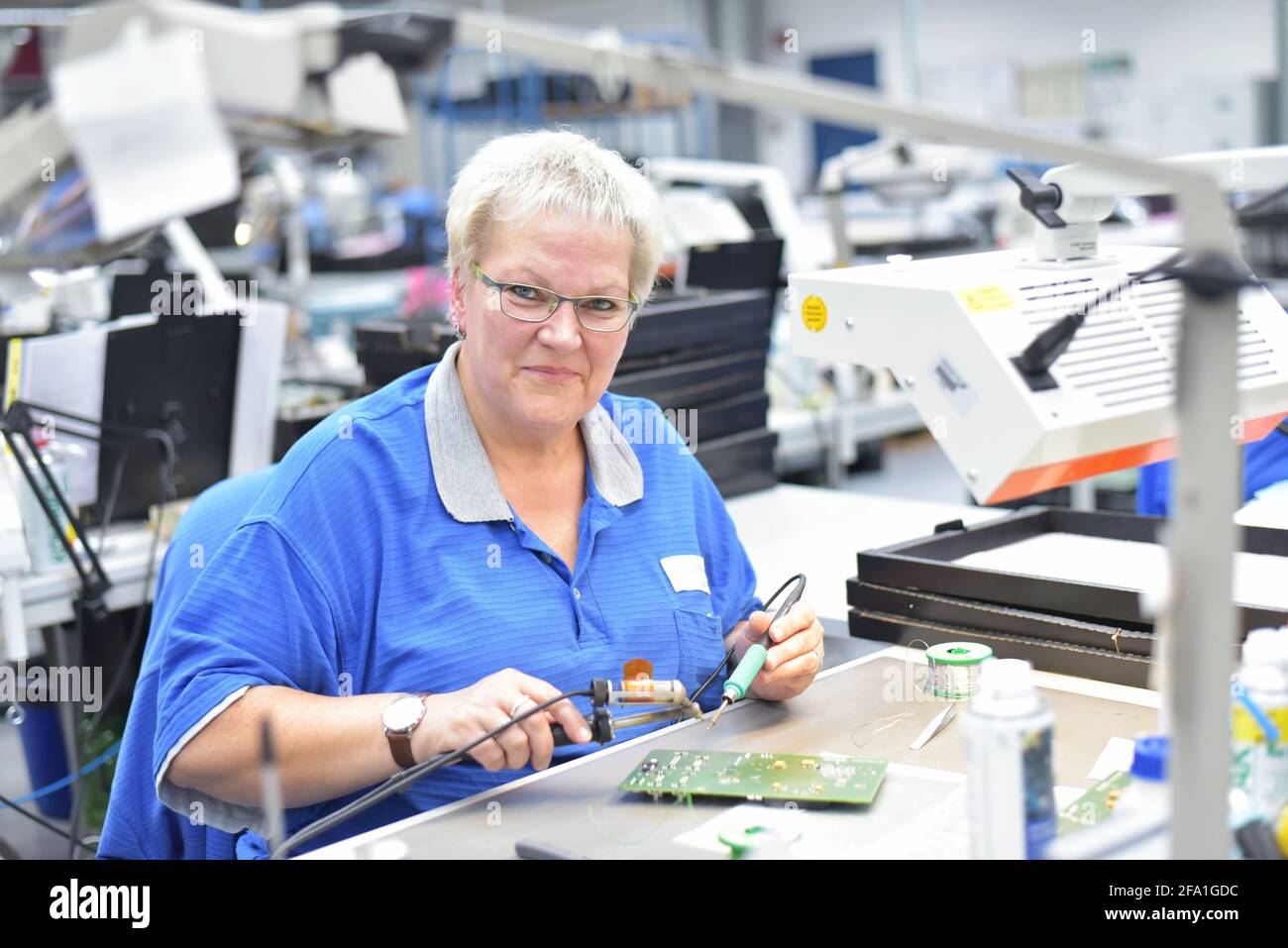 Freundliche Frau in einem mikroelektronikfertigung Factory-Komponenten Montage und Löten arbeiten Stockfoto