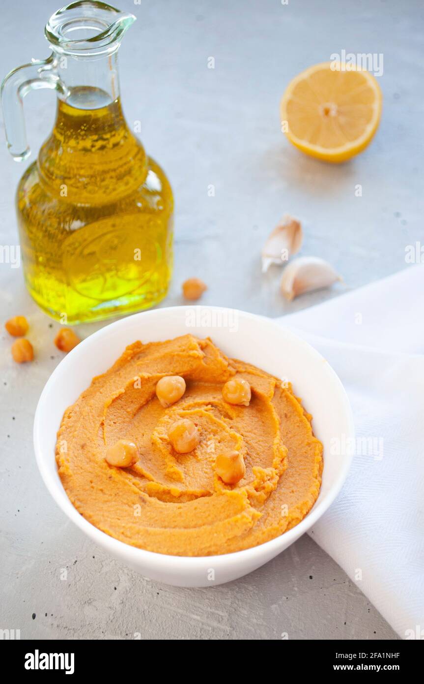 Eine Schüssel mit köstlichem Hummus mit Olivenöl, Knoblauch und Paprika auf grauem Hintergrund. Stockfoto