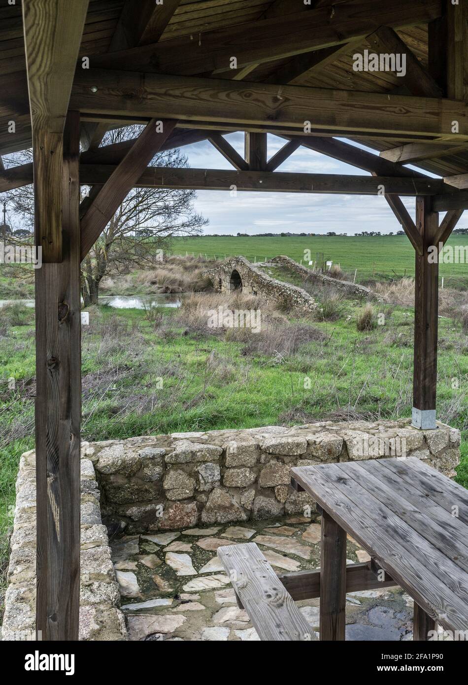 Mittelalterliche Brücke von Santiago de Bencaliz in der Nähe des Dorfes Aldea del Cano, Caceres, Spanien. Überdachter Picknickbereich Stockfoto