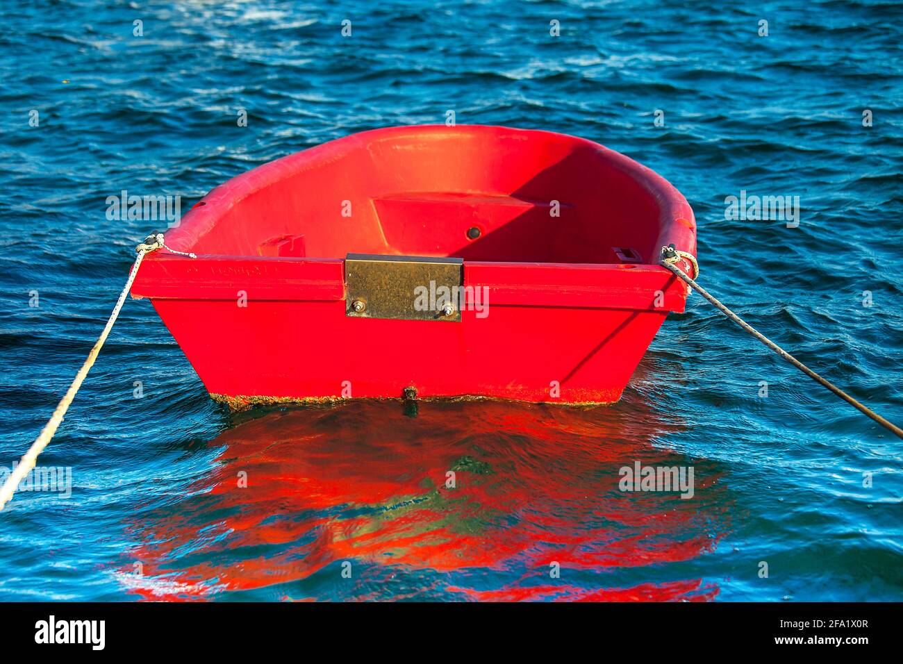 Kleine Beiboot. Isoliert. Rotes Schlauchboot, das in der Marina festgemacht ist. Stockbild. Stockfoto