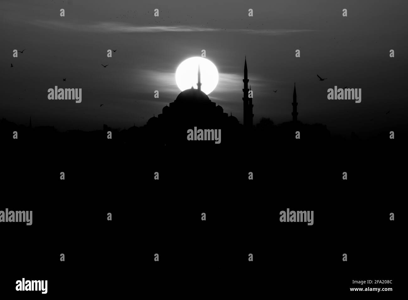 Graustufen-Foto der Suleymaniye Moschee bei Sonnenuntergang. Silhouette der Moschee mit Sonne. islamisches Hintergrundbild. Ramadan, kandil und iftar Hintergrund. Stockfoto