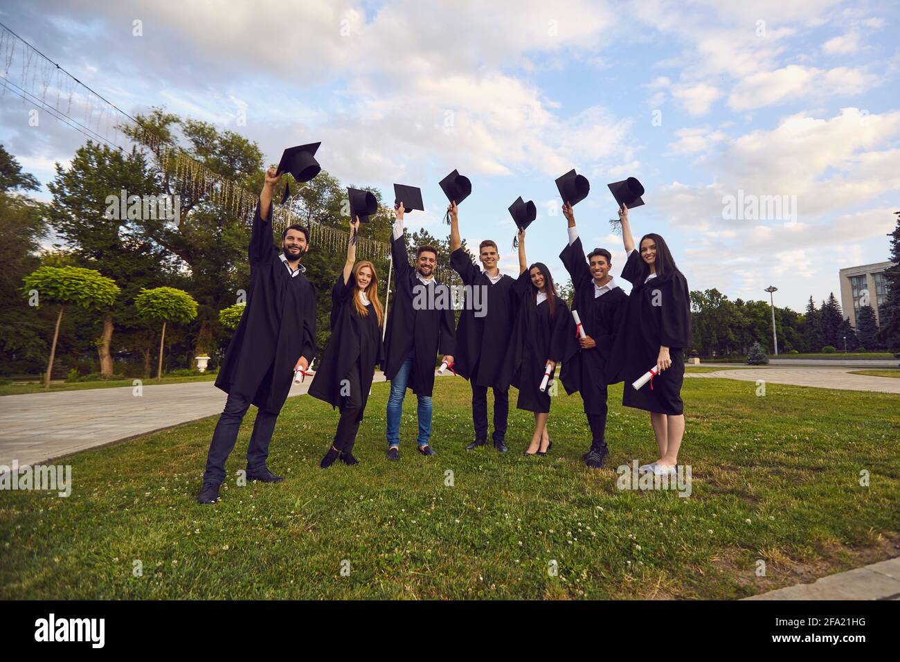 Gruppe von glücklichen Hochschulabsolventen mit Diplomen und Holding Knochen in erhobenen Händen Stockfoto