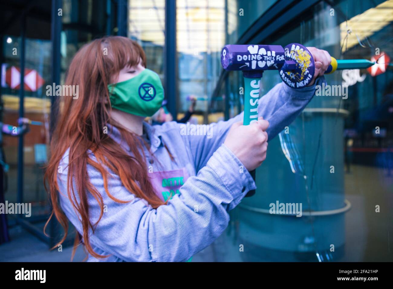 Canary Wharf, London, Großbritannien 22. April 2021 Extinction Rebellion Frauen brechen Fenster bei der HSBC Bank als Teil einer Reihe von Aktionen, aus denen die Geld-Rebellion besteht. Die Umweltgruppe ist wütend über die 80 Milliarden Pfund schweren Investitionen der Bank in fossile Brennstoffe in den letzten 5 Jahren Stockfoto