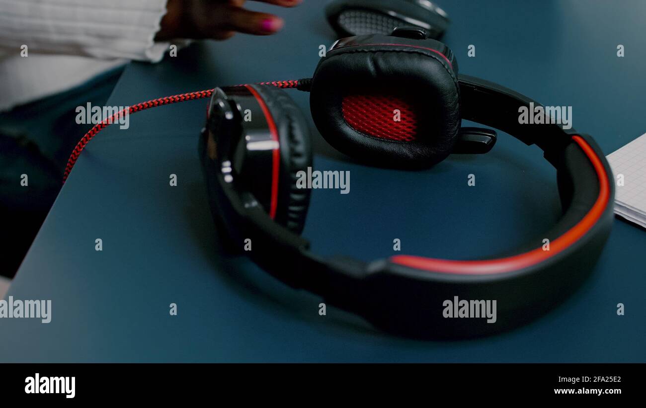 Schwarzer Videoeditor, der mit Filmmaterial auf dem pc mit zwei Monitoren arbeitet und Kopfhörer aufsetzt. Afrikanischer Videofilmer, der mit Post-Production-Software Filme bearbeitet, die in einem Büro der Kreativagentur arbeitet. Stockfoto