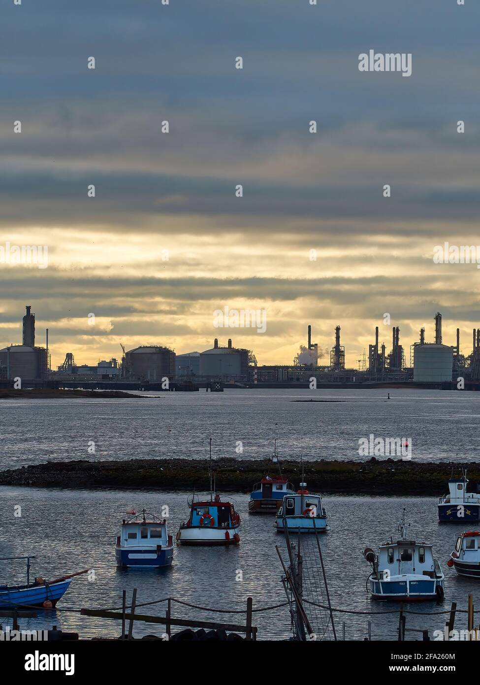 Ein Blick über Paddy’s Hole, South Gare, mit Blick auf die kleinen Boote der Fischereiflotte und die Mega-Strukturen der Containerhäfen am Horizont. Stockfoto