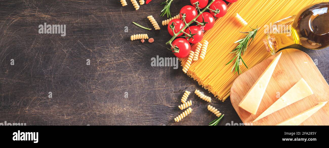 Ungekochte Pasta auf Holzhintergrund. Draufsicht. Rohe Pasta mit Zutaten zum Kochen. Lebensmittelkonzept. Italienisches Essen. Stockfoto