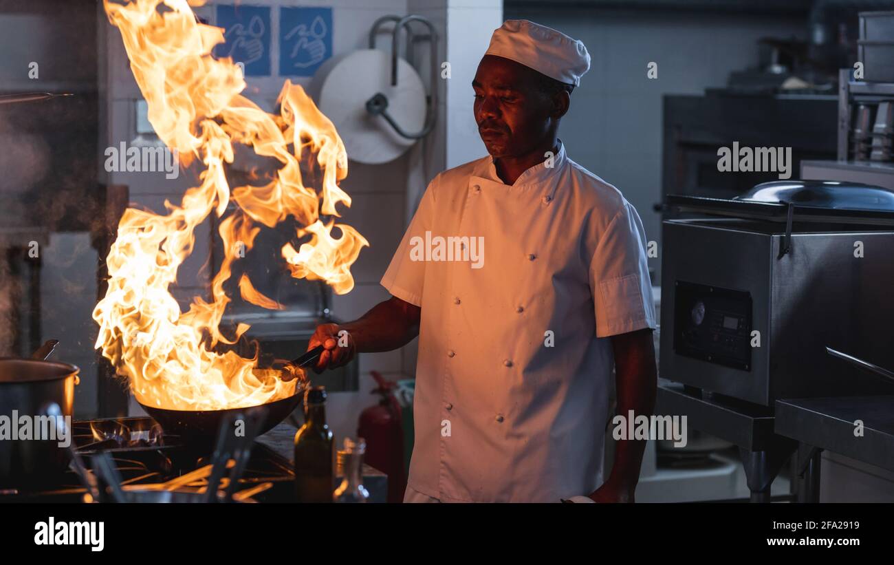 afroamerikanischer Profi-Koch flambiert Gericht im Wok Stockfoto