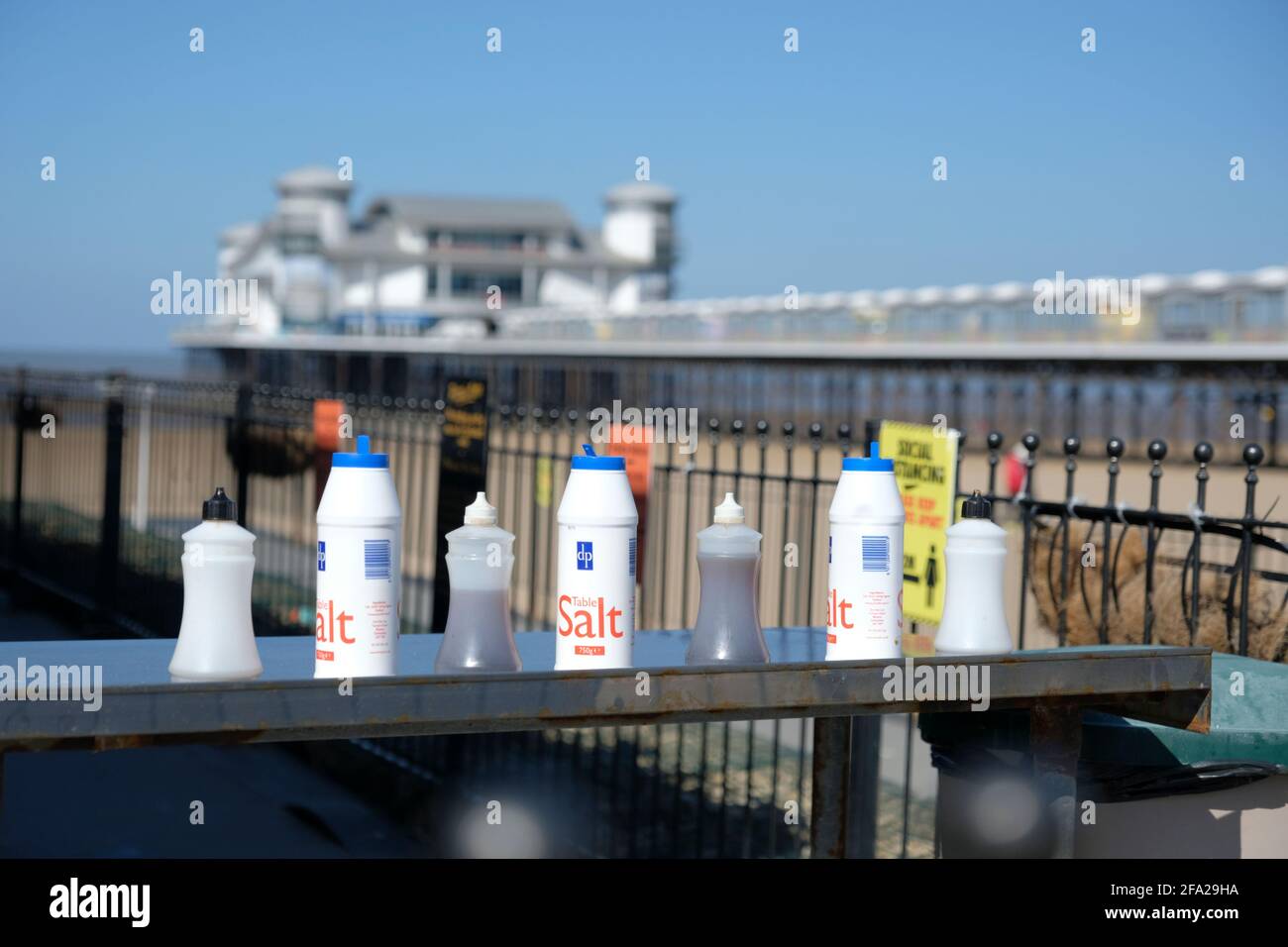 Salz und Essig auf einem Fisch- und Chipstand. Weston-super-Mare Grand Pier im Hintergrund Stockfoto