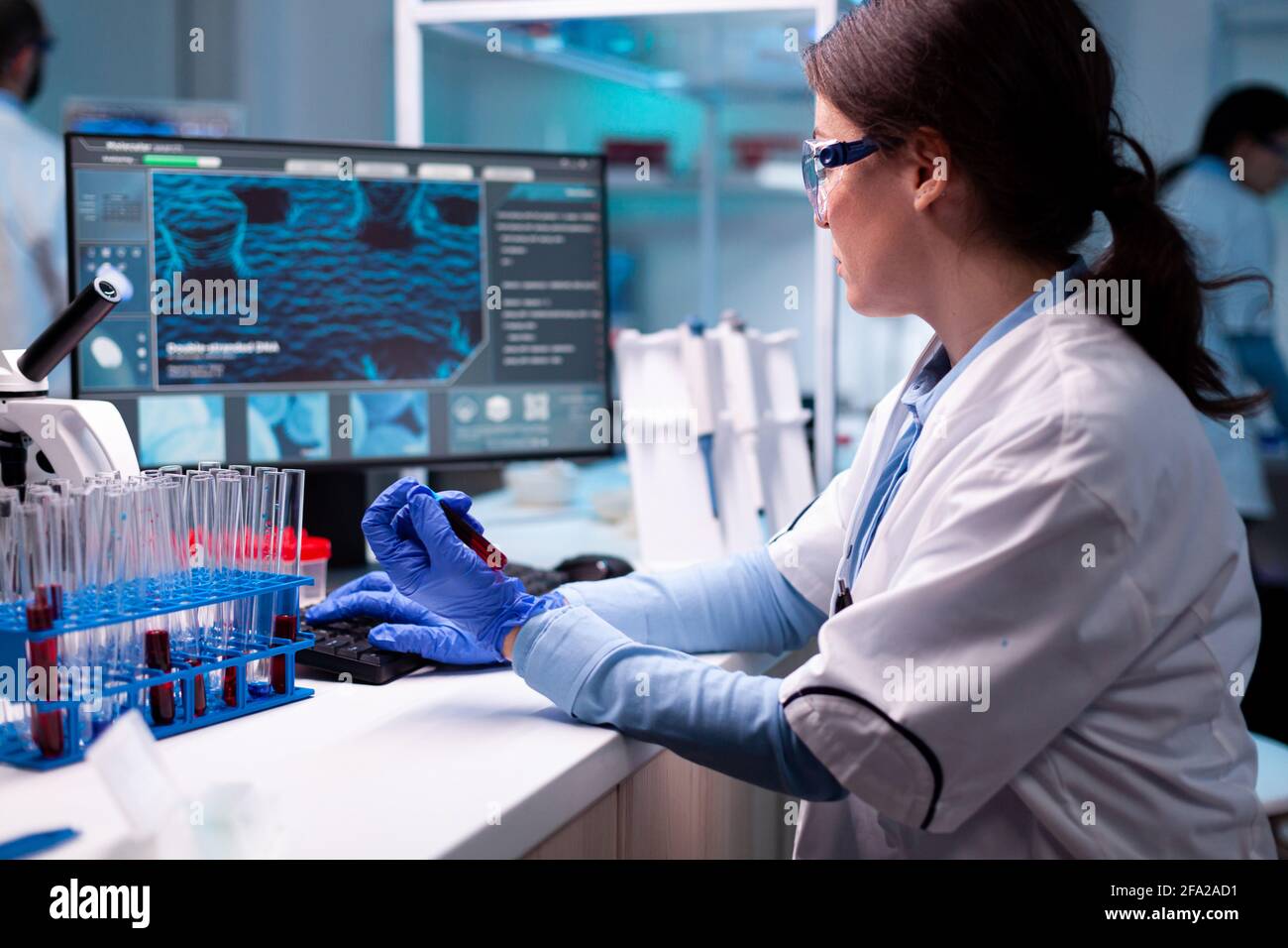 Wissenschaftler tippen auf Laptop mit Vacutainer Blut Chemie im Gesundheitswesen. Forscher im Labor für chemische Medizin, der mit professionellen Technologiegeräten für die Entwicklung des Gesundheitswesens arbeitet. Stockfoto