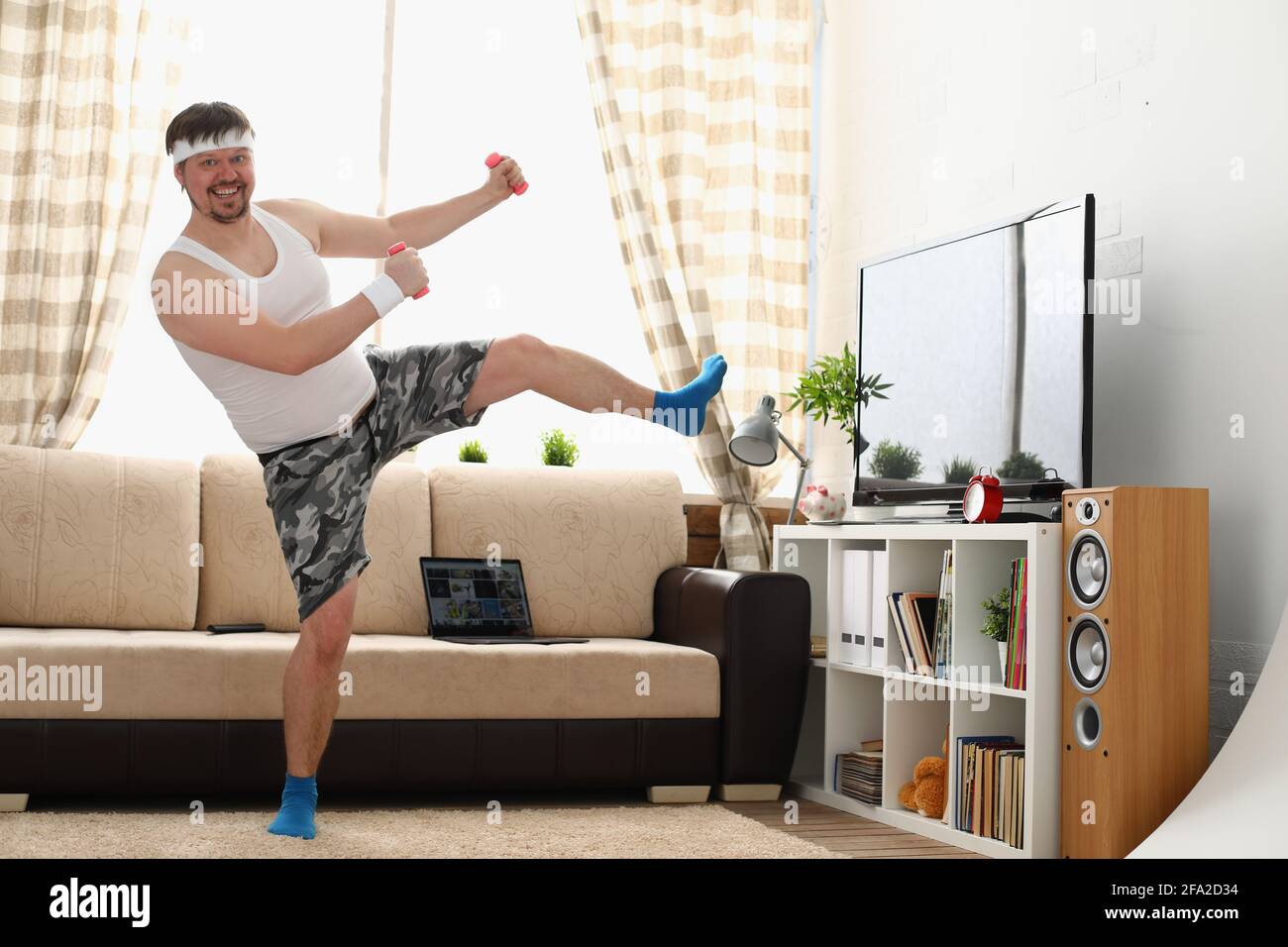 Der dicke Mann in Sportbekleidung und Kurzhanteln macht körperliche Bewegung Stockfoto