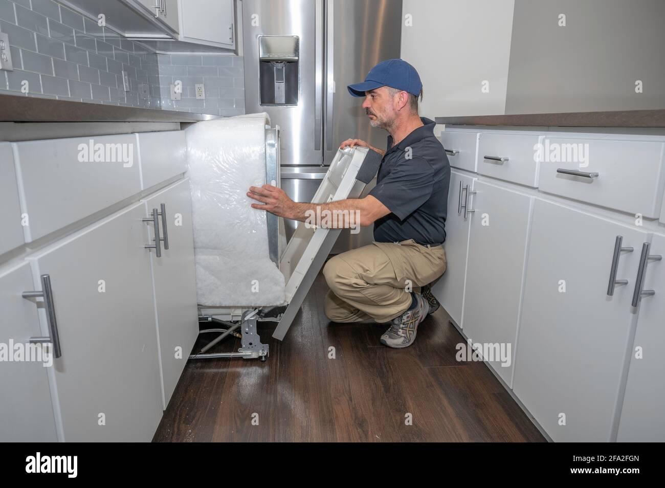 Hausgerätepirmann installiert einen Geschirrspüler in einem modernen Zuhause Stockfoto