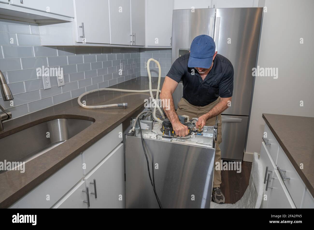 Geräterepiratur, die auf dem Boden eines Geschirrspülers in arbeitet Eine moderne Küche Stockfoto