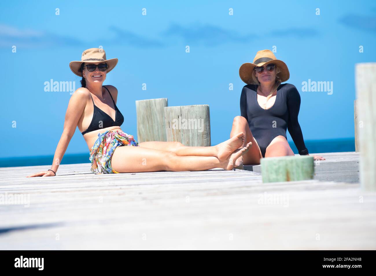 Zwei Frauen, die sich auf einem Dock in der Karibik entspannen Stockfoto