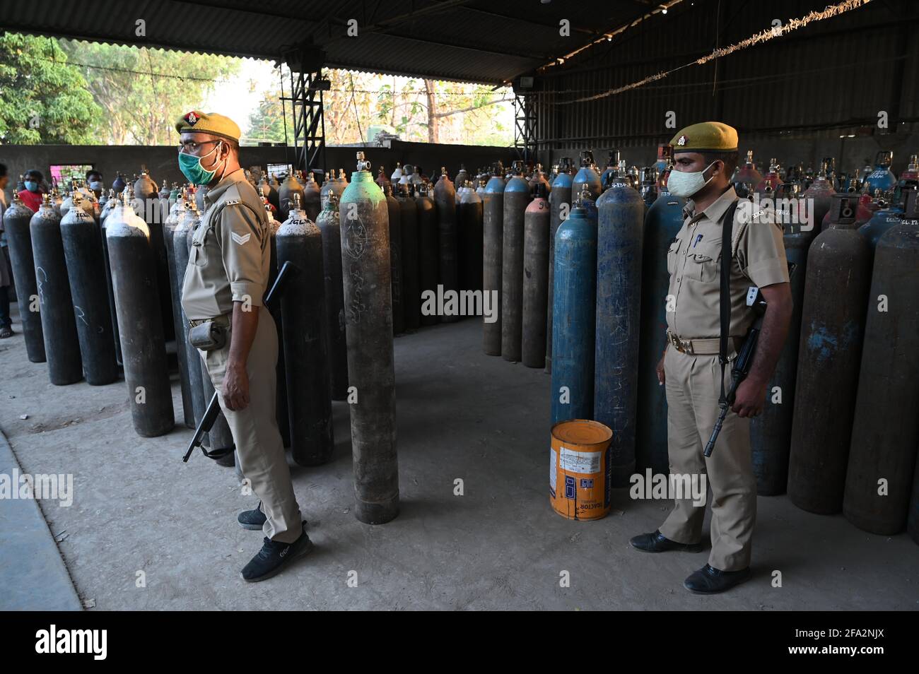 Prayagraj, Uttar Pradesh, Indien. April 2021. Prayagraj: Polizist wacht, während Familienmitglieder von COVID-19-Patienten warten, um ihre leeren Flaschen mit medizinischem Sauerstoff außerhalb eines Sauerstofffüllzentrums zu füllen, da die Nachfrage nach Gas aufgrund von Spitzen bei Coronavirus-Fällen am Donnerstag, dem 22. April 2021, in Prayagraj steigt. Quelle: Prabhat Kumar Verma/ZUMA Wire/Alamy Live News Stockfoto