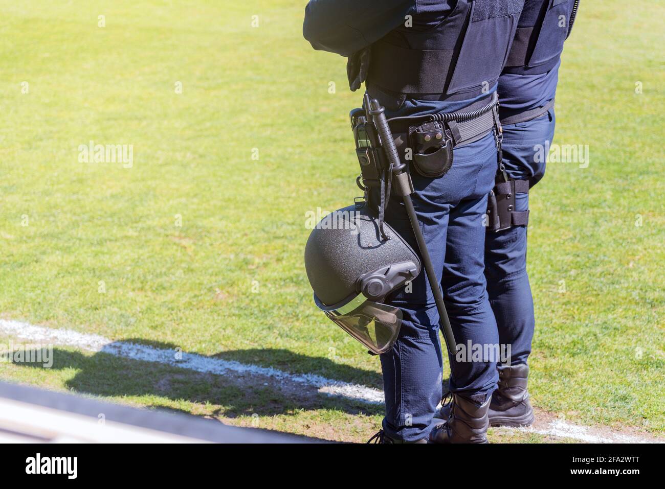 Zwei Bereitschaftspolizisten, die mit unterschiedlichen Schutzvorrichtungen auf dem Feld eines Fußballfeldes ausgestattet sind. Stockfoto