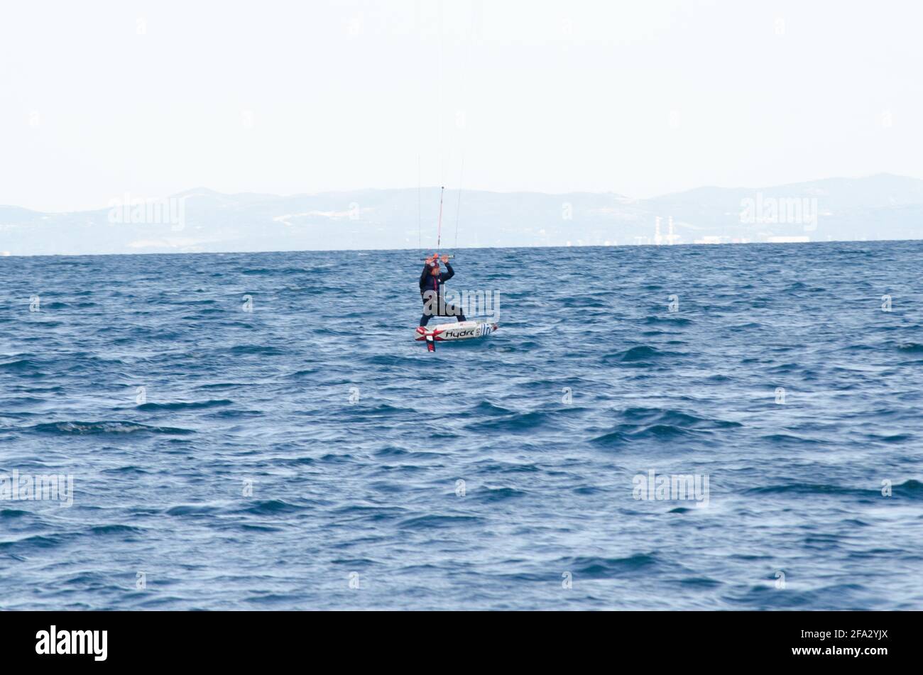 Ein Kiteboarder wird über das Wasser gezogen Tragen Sie einen Neoprenanzug in Mildes bis kaltes Wasser Stockfoto