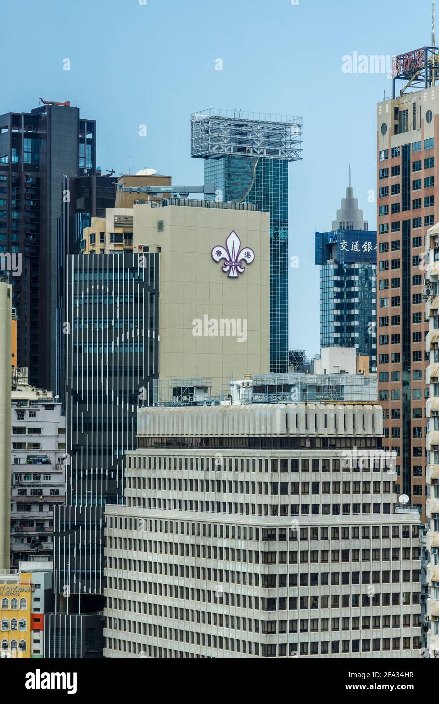 Das Hochhaus in Hongkong und in seiner Mitte das Abzeichen der Pfadfindervereinigung, Fleur de Lis, China. Gegründet 1914. Stockfoto