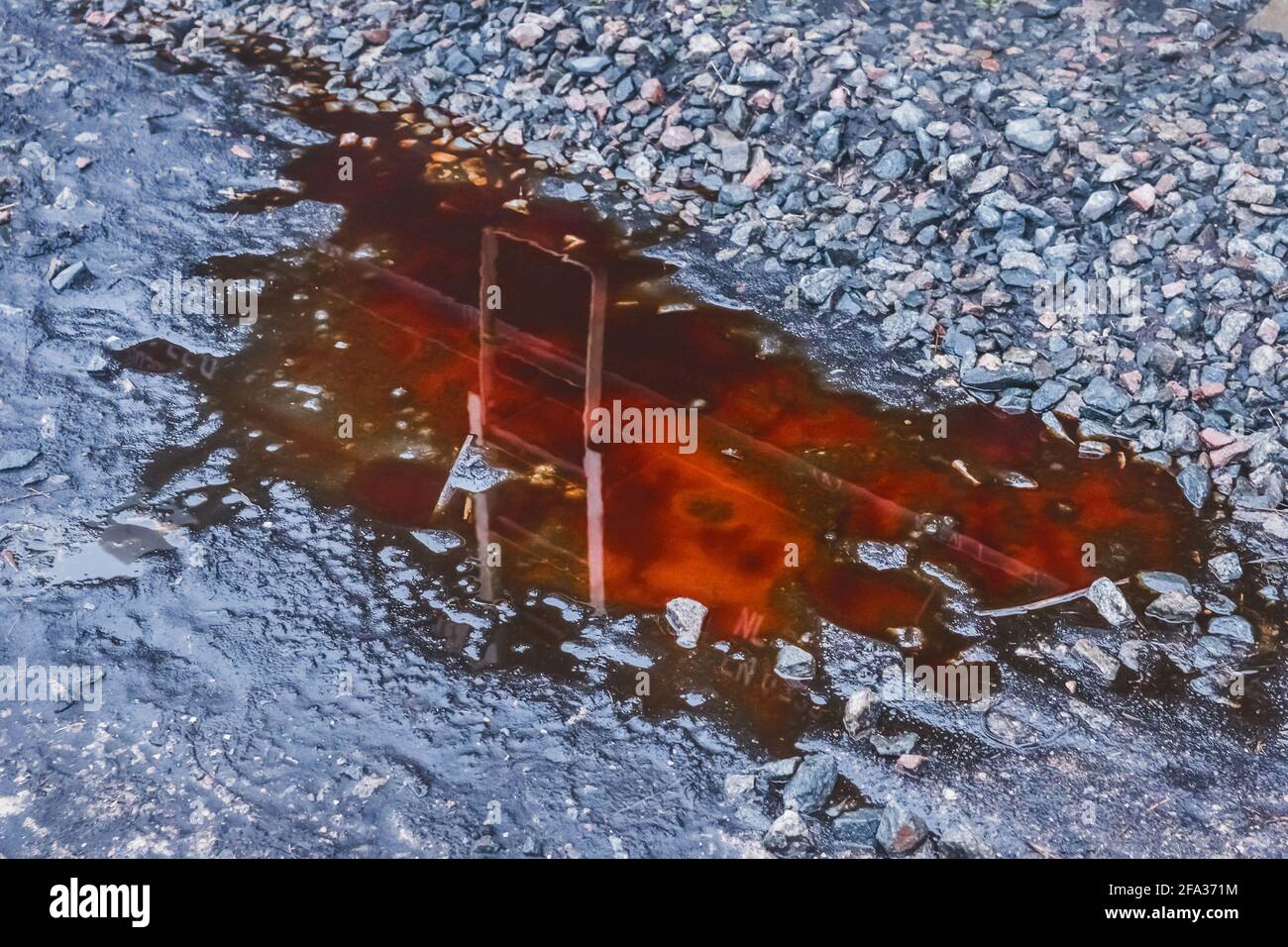 Pfütze von rotem Kali-Dünger nach Regen auf zerkleinerten Steinen einer landwirtschaftlichen Industrieanlage. Stockfoto