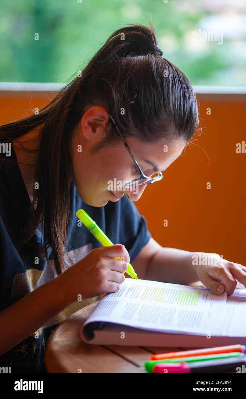 Universitätsstudentin, die für eine Prüfung studiert und Text mit Textmarker unterlegt. Stockfoto