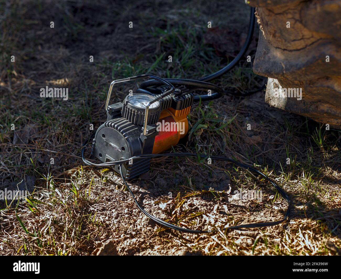 Elektrischer Kompressor mit Messgerät auf dem Boden neben dem Traktorrad. Stockfoto