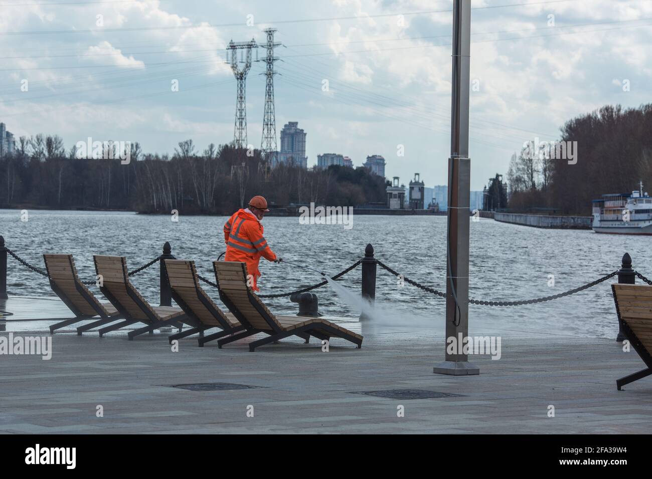 Moskau, Russland - 22 2021. April: Stadtarbeiter reinigen den Damm mit Hochdruckwasserausrüstung. Stockfoto