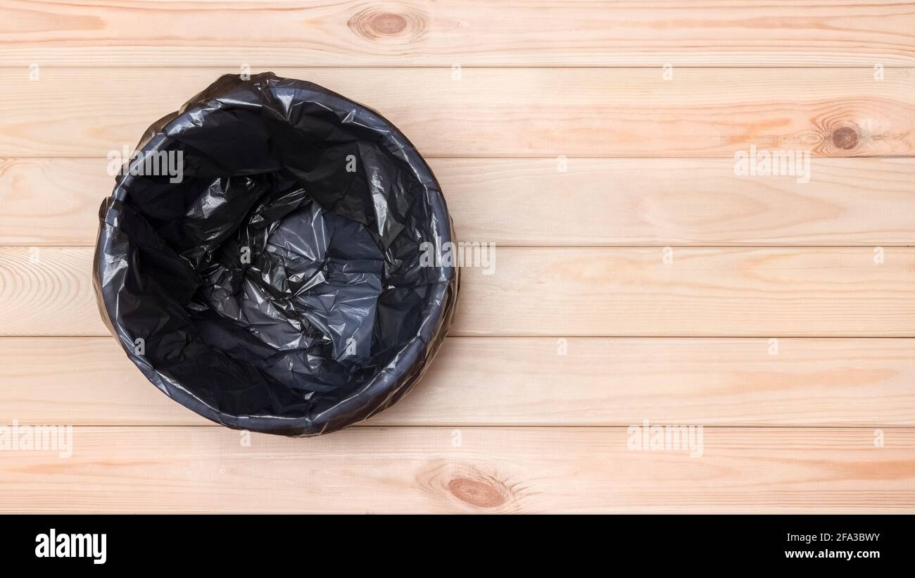 Papierkorb – Ansicht Von Oben. Banner Für Leeren Papierkorb. Schwarze Tasche in einem Papierkorb. Abfalleimer. Leeren Sie den Papierkorb auf dem Holzboden. Abfalleimer auf Holzhintergrund. Abfall Stockfoto