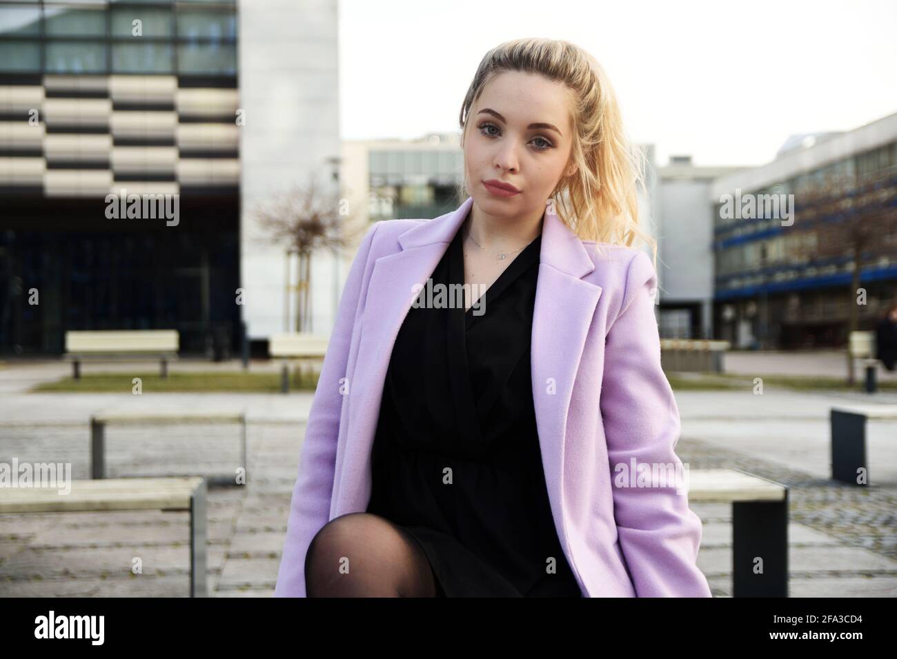Junge Frau in Breslau. Studentin mit blonden Haaren, mit violettem Mantel. Stockfoto