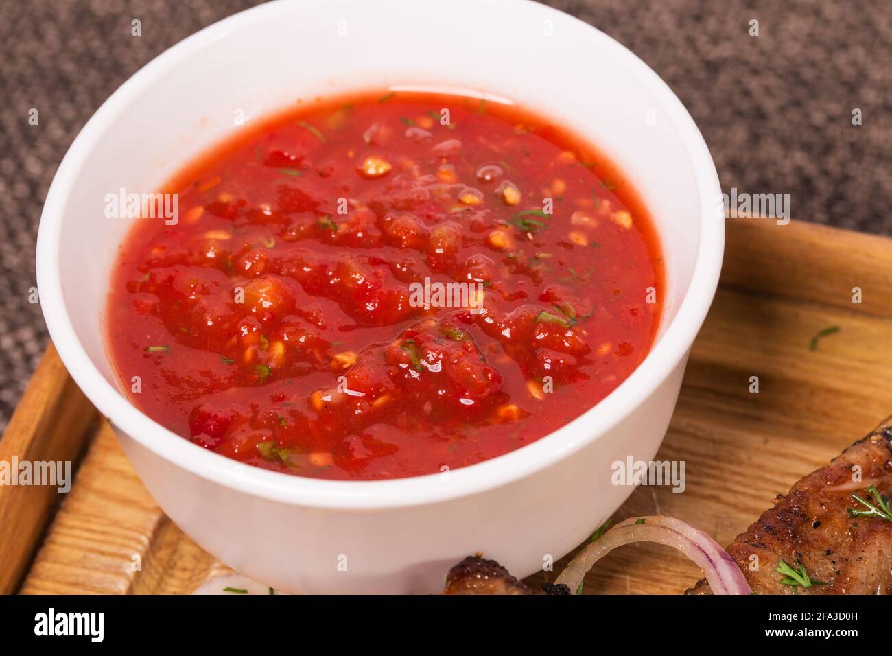Würzige Tomatensauce mit Kräutern für gegrilltes Fleisch auf Platte mischen. Makro. Foto kann als ganzer Hintergrund verwendet werden. Stockfoto