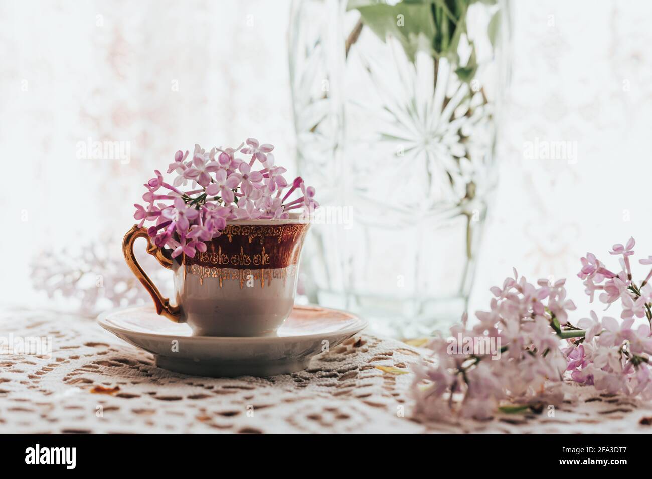 Retro-Teetasse mit Fliederblüten darin. Heimtextilien. Frühlingsstimmung. Platz für Text Stockfoto