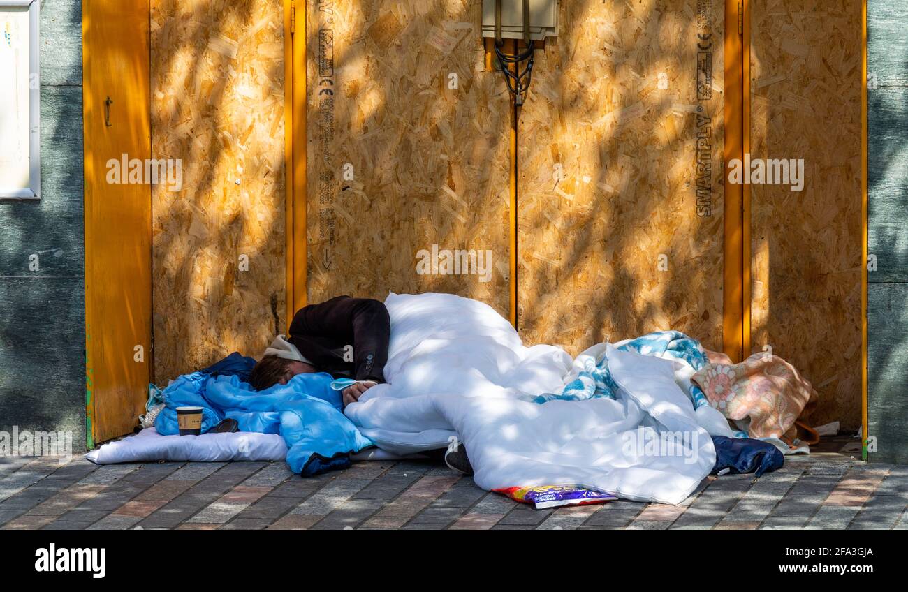 Obdachlose Person schläft rau in der Tür des Ladens. Stockfoto