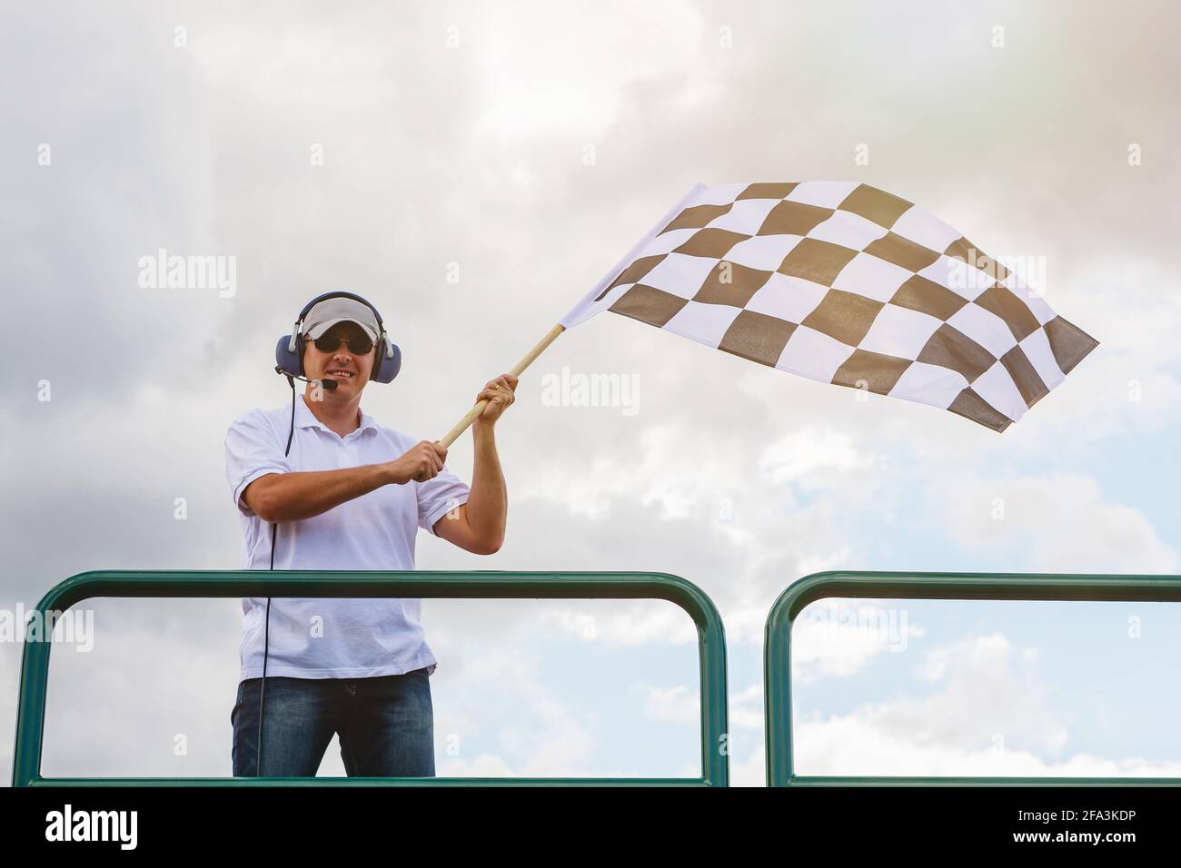 Mann winkt eine karierte Flagge an der Ziellinie von Das Rennen Stockfoto