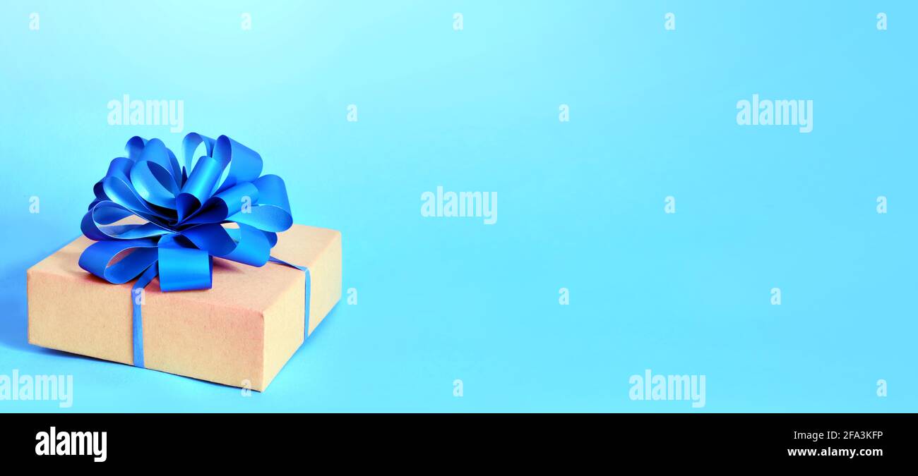 Geschenkkarton aus Pappe mit lila Schleife auf blauem Hintergrund. Stockfoto