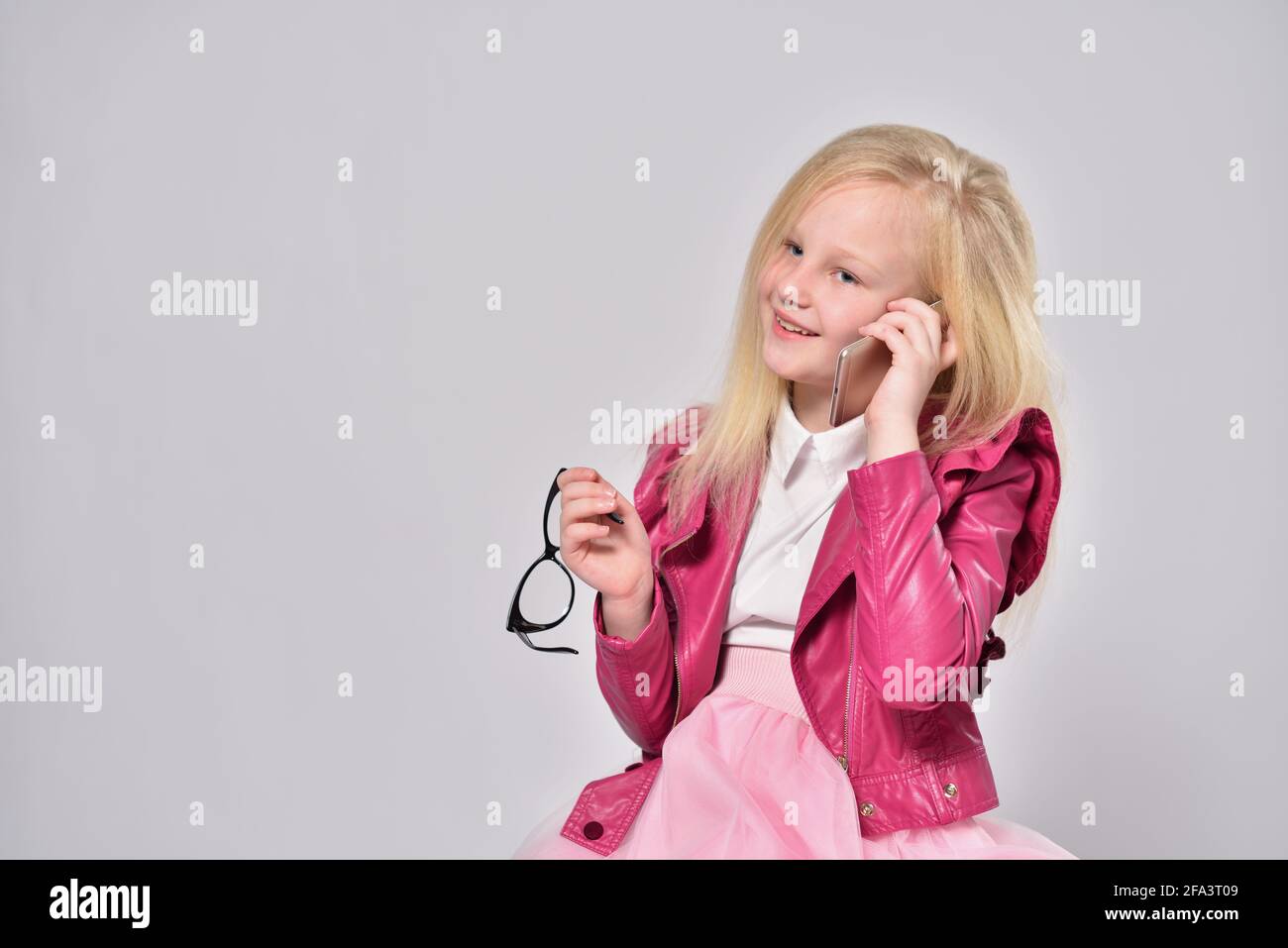 Kind Mädchen in einer rosa Jacke reden am Telefon Stockfoto