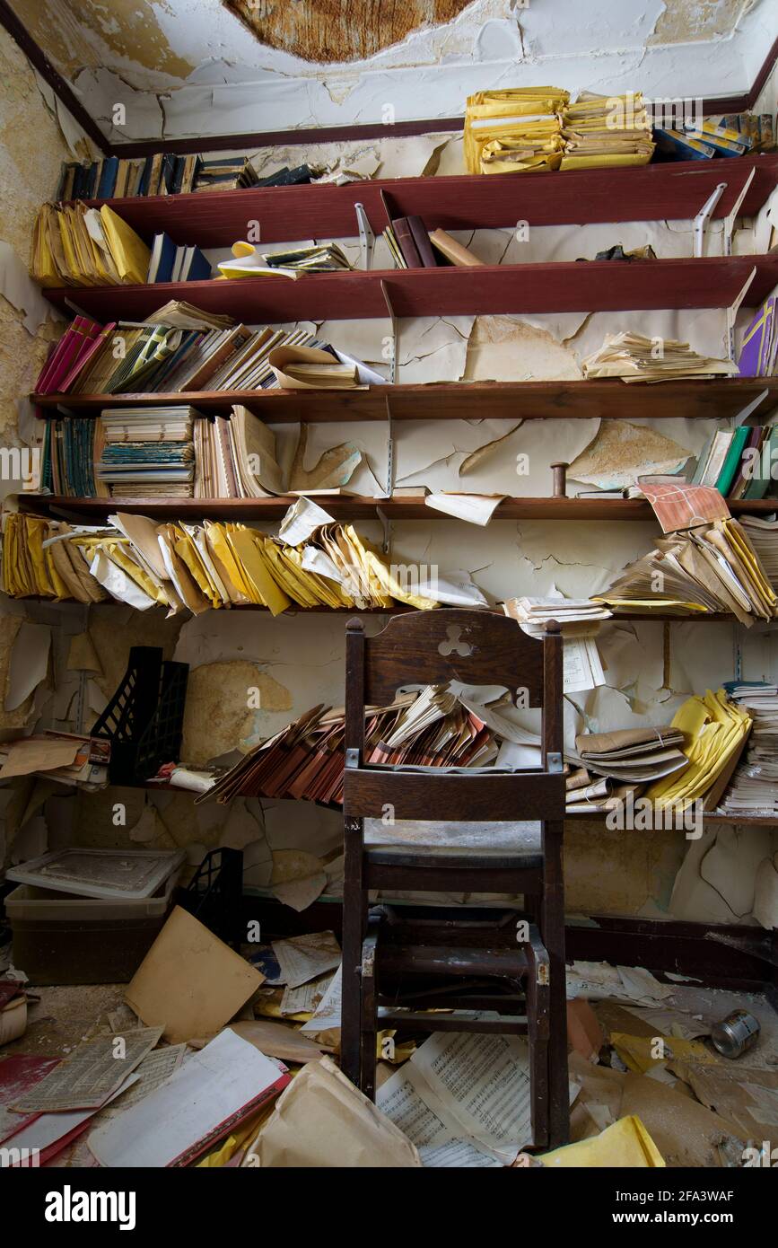 Bücherregale mit Büchern und Dokumenten in einer alten und verfallenen Kirche. Stockfoto