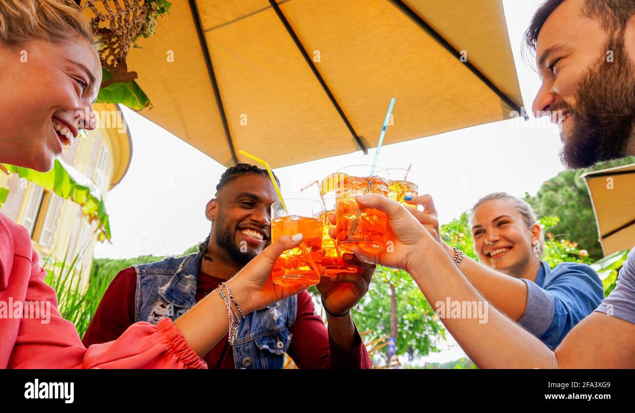 Eine Gruppe junger Leute, die im Sommer in einer Bar bei Getränken Spaß haben - Freunde, die mit einem Coktail jubeln und miteinander lachen Stockfoto