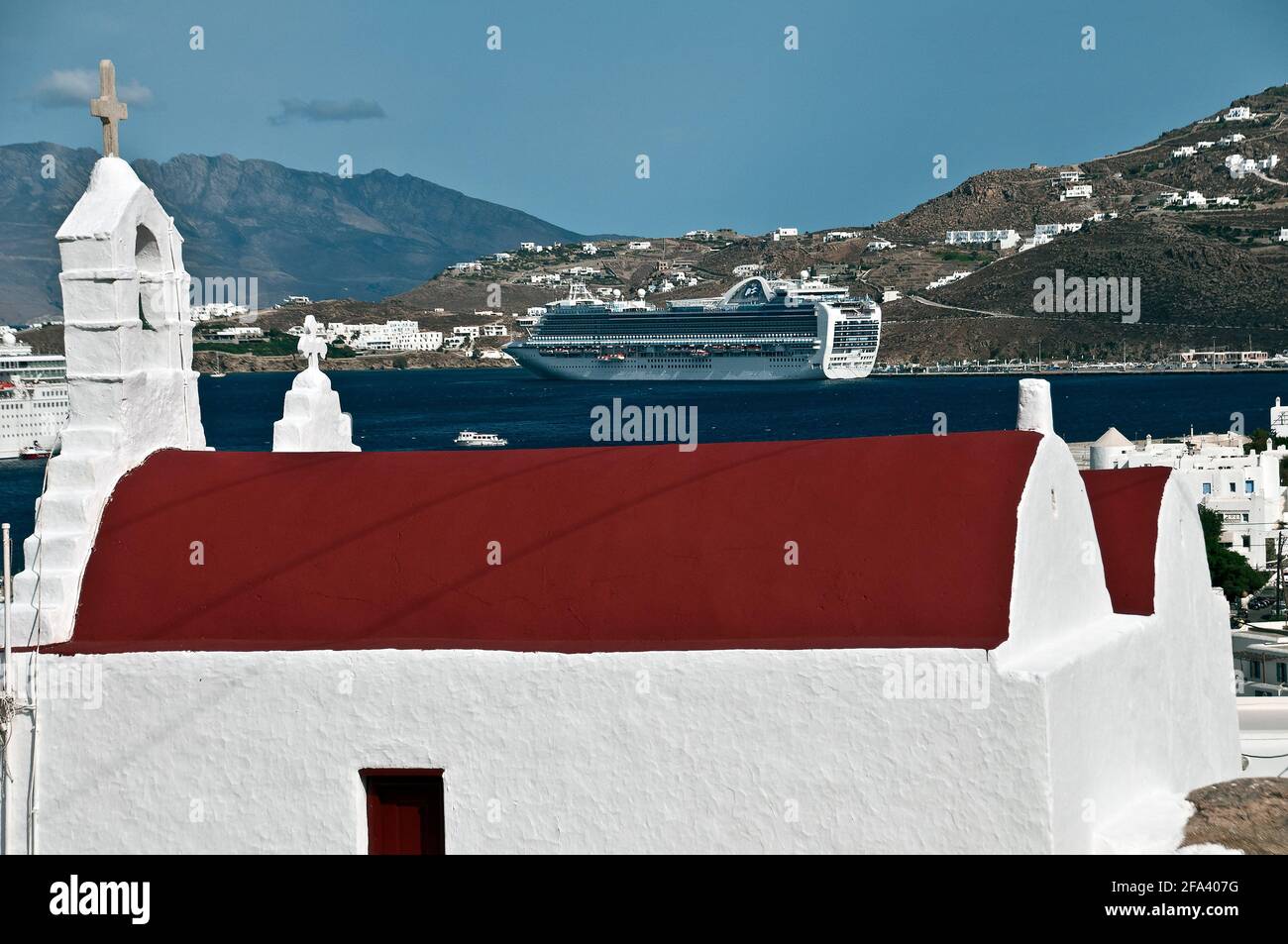 Rot überdachte Kirche, Kreuzfahrtschiff, das in der Ferne im Hafen festgemacht ist, Mykonos, Griechenland Stockfoto