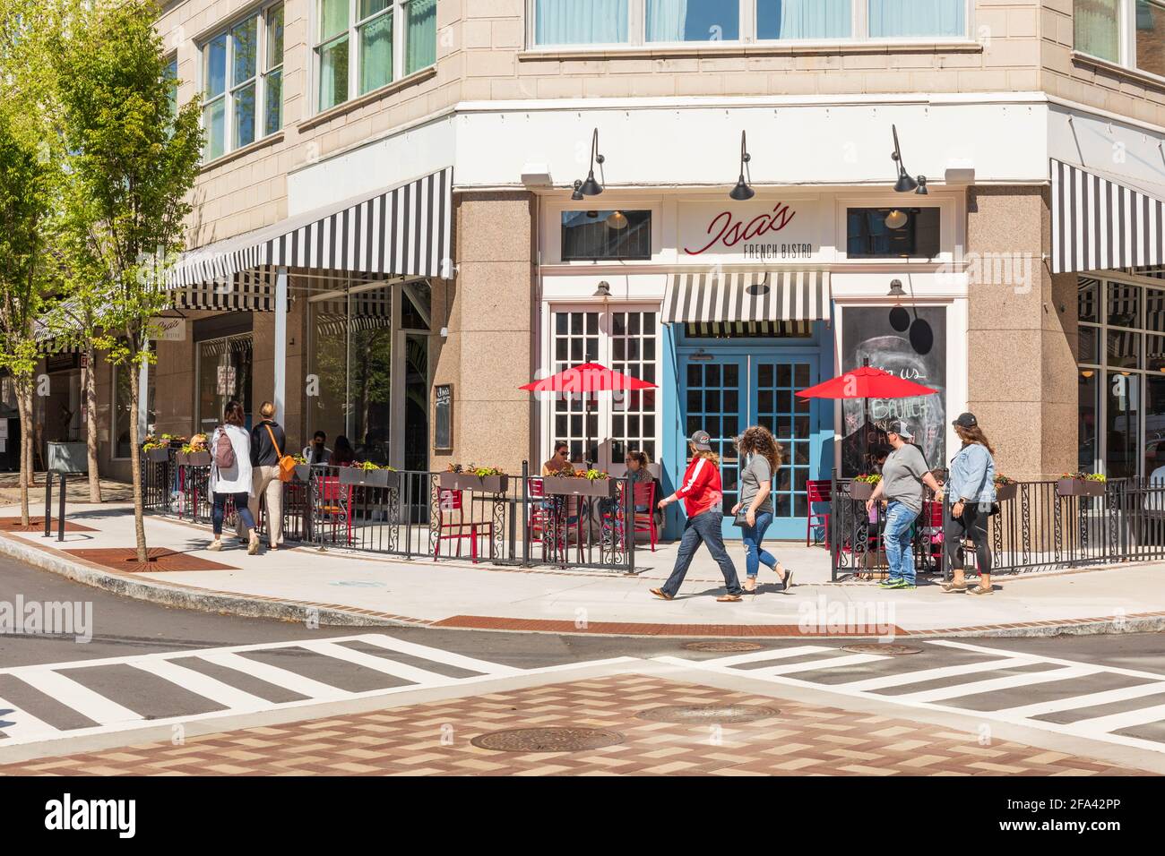 ASHEVILLE, NC, USA-11 APRIL 2021: ISA's French Bistro, an einer Ecke in der Innenstadt, mit Leuten, die an Tischen im Freien sitzen und anderen, die vorbei gehen. Stockfoto