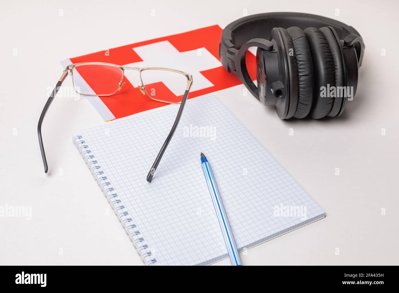 Fremdsprachen lernen in der Schweiz mit Audioaufnahmen und Kopfhörern. Notizblock, Brille, Stift. Stockfoto