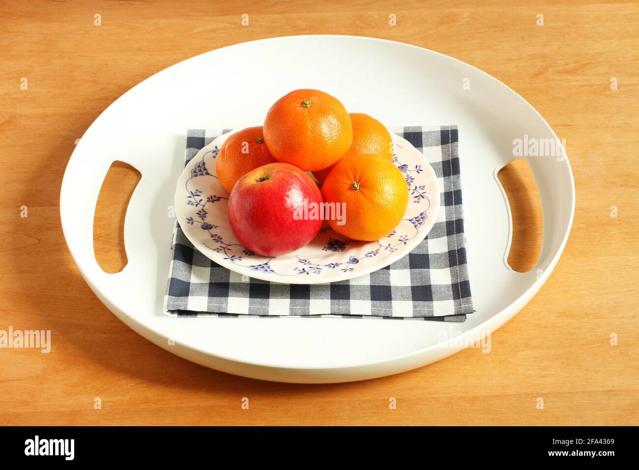 Weißes Kunststofftablett mit Äpfeln und Mandarinen in einem Teller auf einem Holztisch. Nahaufnahme Stockfoto