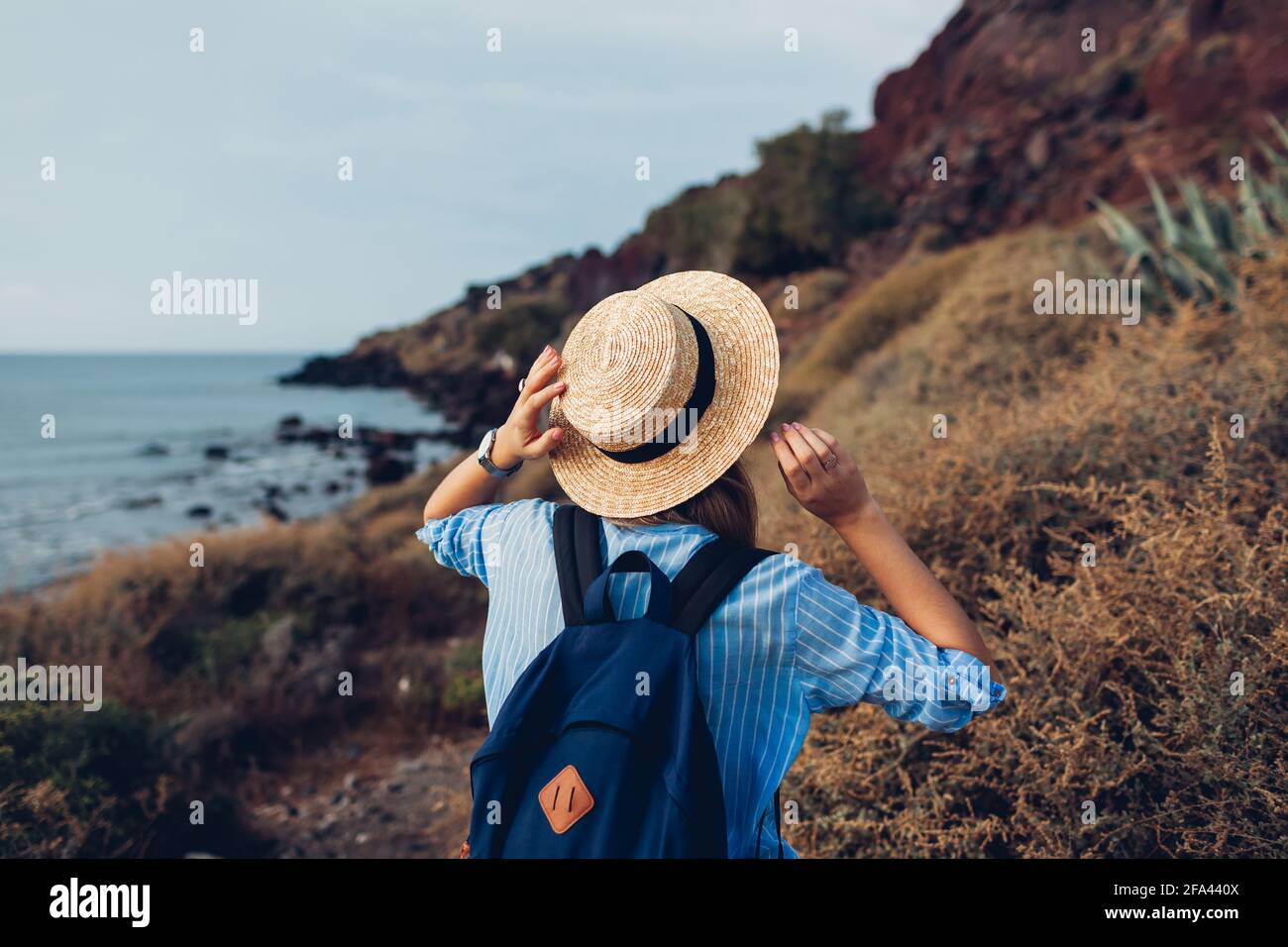 Frau, die am Strand in Akrotiri, Santorini Insel, Griechenland am Ägäischen Meer entlang läuft und die Landschaft genießt. Tourismus, Sommerreisen Stockfoto