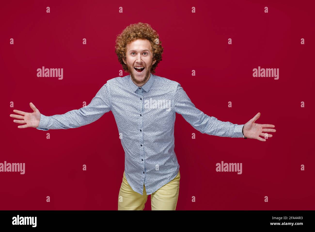 Der junge, lockig reife Mann, der ein elegantes Hemd trägt und einen Sieg oder Erfolg feiert, ist überrascht und schockiert Stockfoto