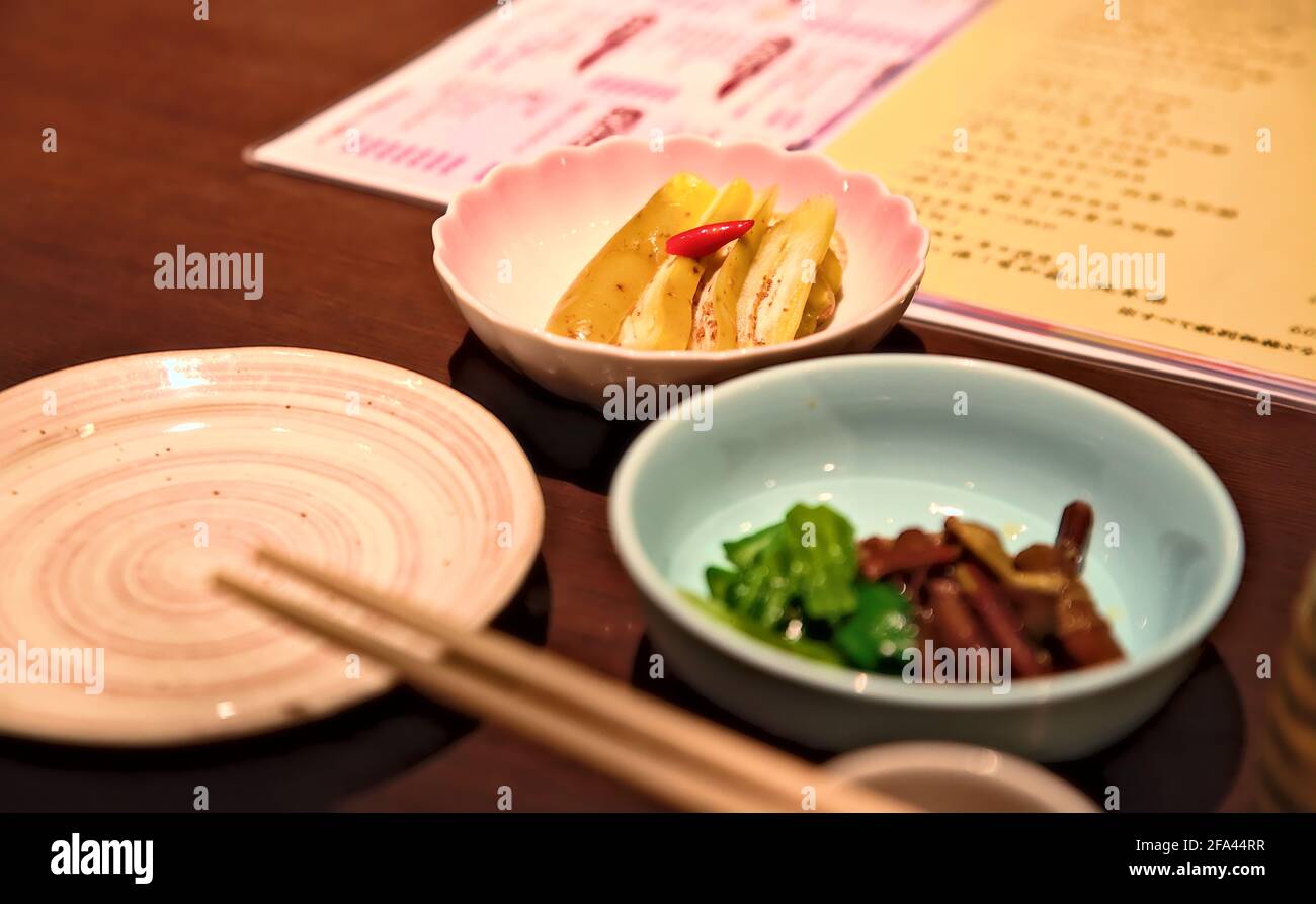 Selektive Konzentration auf eine kleine Schale Pesora-zuke, eine traditionelle eingelegte Auberginen-Schale aus der Yamagata-Region Japans, auf einem Holztisch Stockfoto