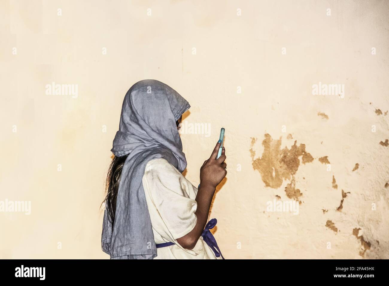 Frau Tourist in römischen Kostümen in Bath England gekleidet nimmt Ein Selfie gegen eine alte, grungige römische Mauer Stockfoto