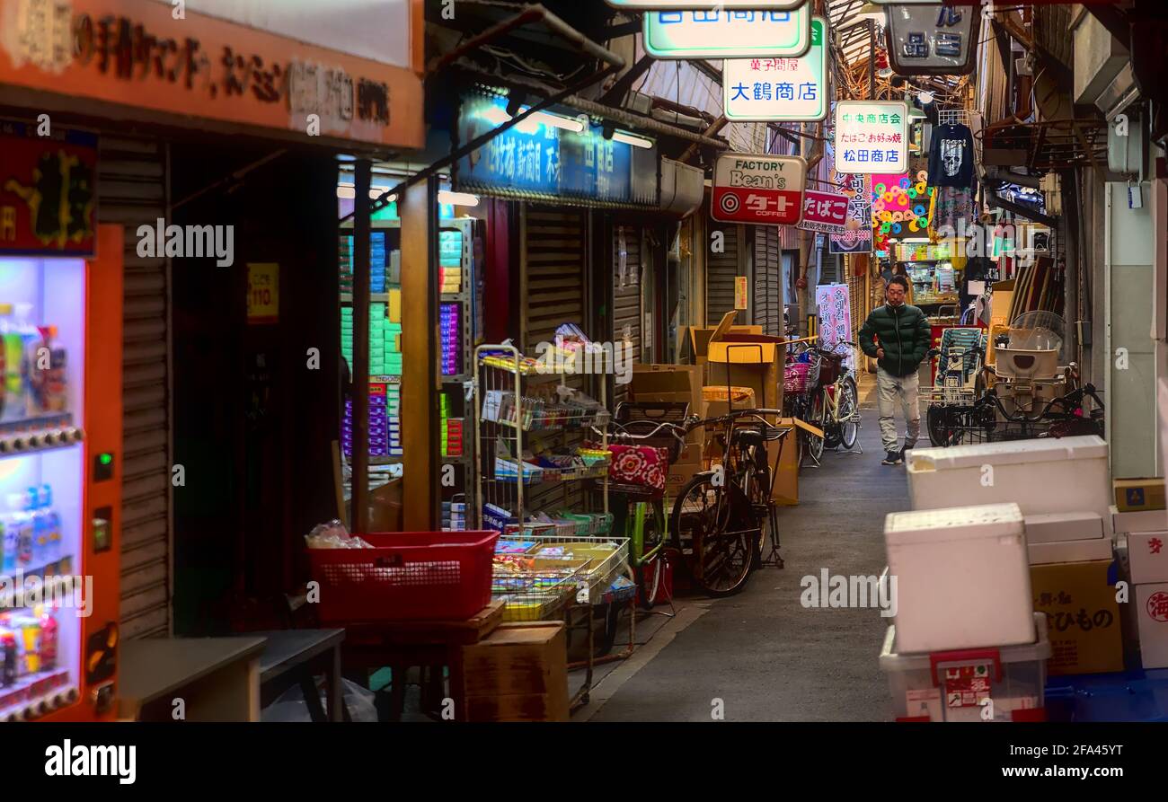 Osaka, Japan - 5 2020. November: Ein Mann mittleren Alters, der durch eine schmale, überdachte Einkaufsstraße im Tsuruhashi-Viertel von Osaka geht Stockfoto